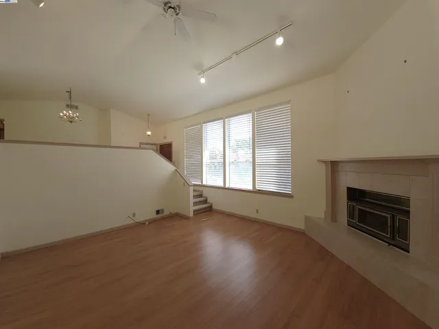 an empty room with wooden floor fireplace and windows
