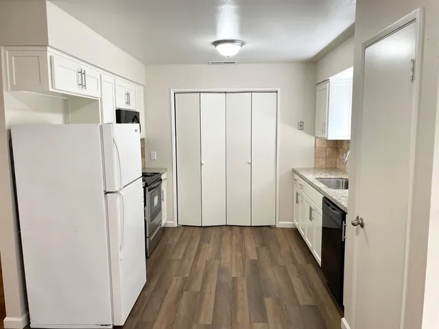 a kitchen with a refrigerator a sink and dishwasher with wooden floor