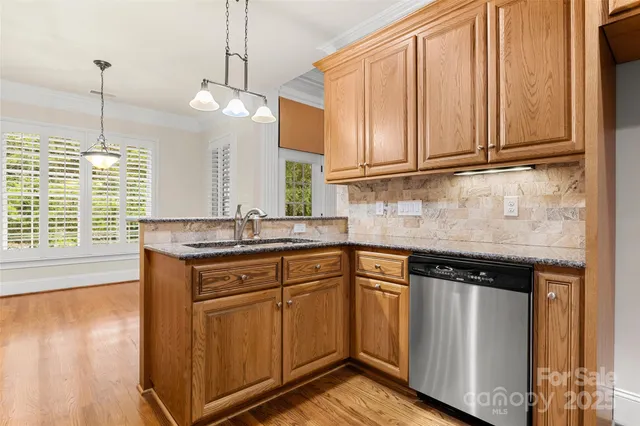 a kitchen with stainless steel appliances granite countertop a sink a stove and a wooden floors