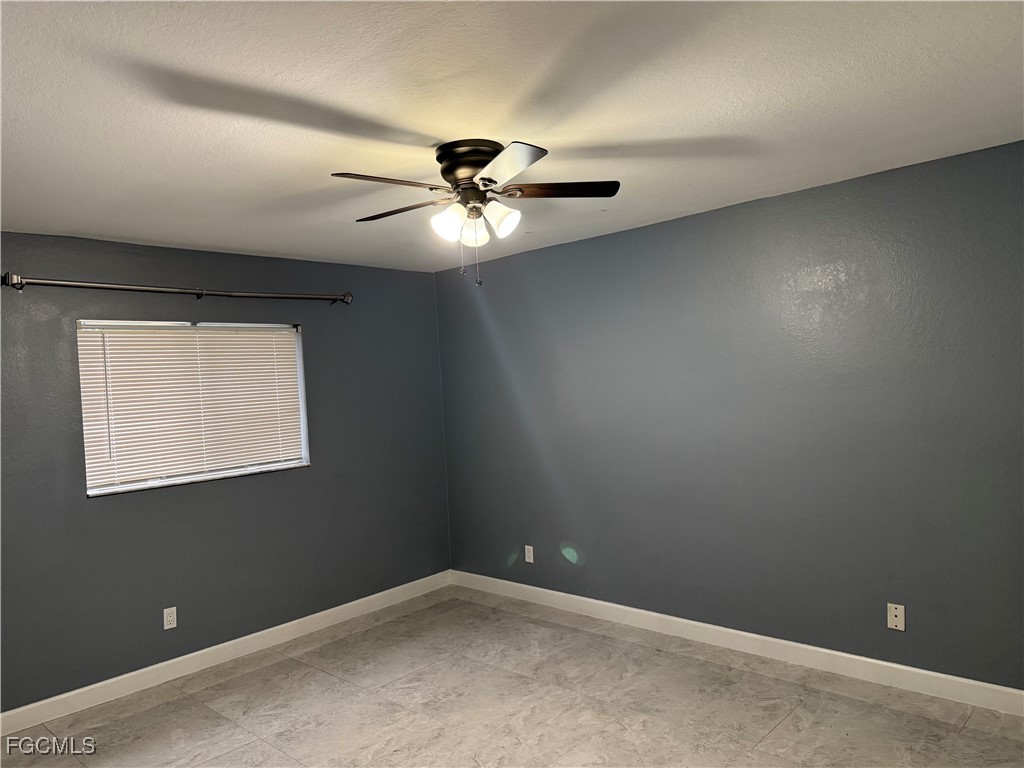 3509 8th Street Southwest Lehigh Acres, FL 33976 - Photo 6 of 14 an empty room with a window and a fan