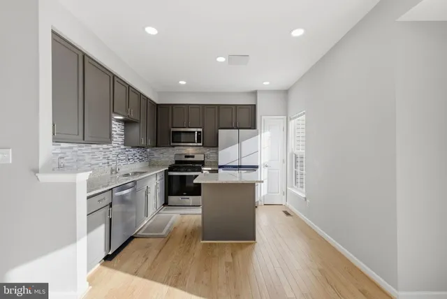 a kitchen with kitchen island a sink a stove a refrigerator and white cabinets
