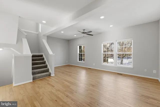a view of an empty room with wooden floor and stairs
