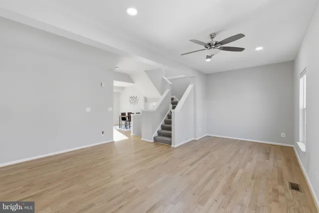an empty room with wooden floor fan and windows