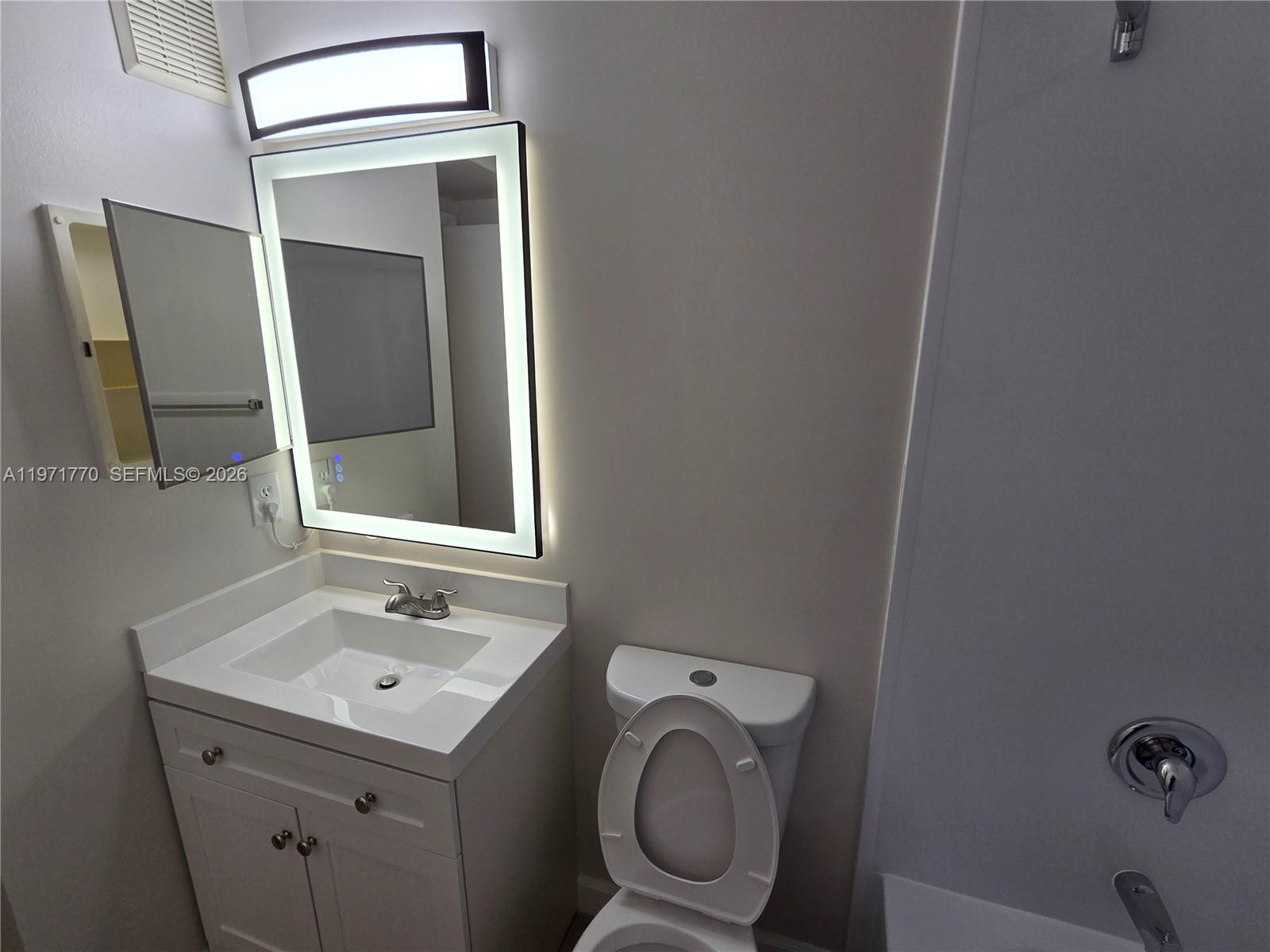 12490 Southwest 54th Street, Unit 12490 Miramar, FL 33027 - Photo 5 of 7 a bathroom with a sink a toilet and mirror