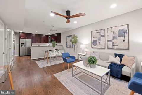a living room with furniture kitchen view and a wooden floor