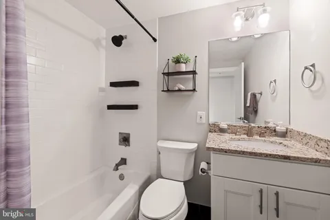 a bathroom with a granite countertop sink mirror vanity and toilet