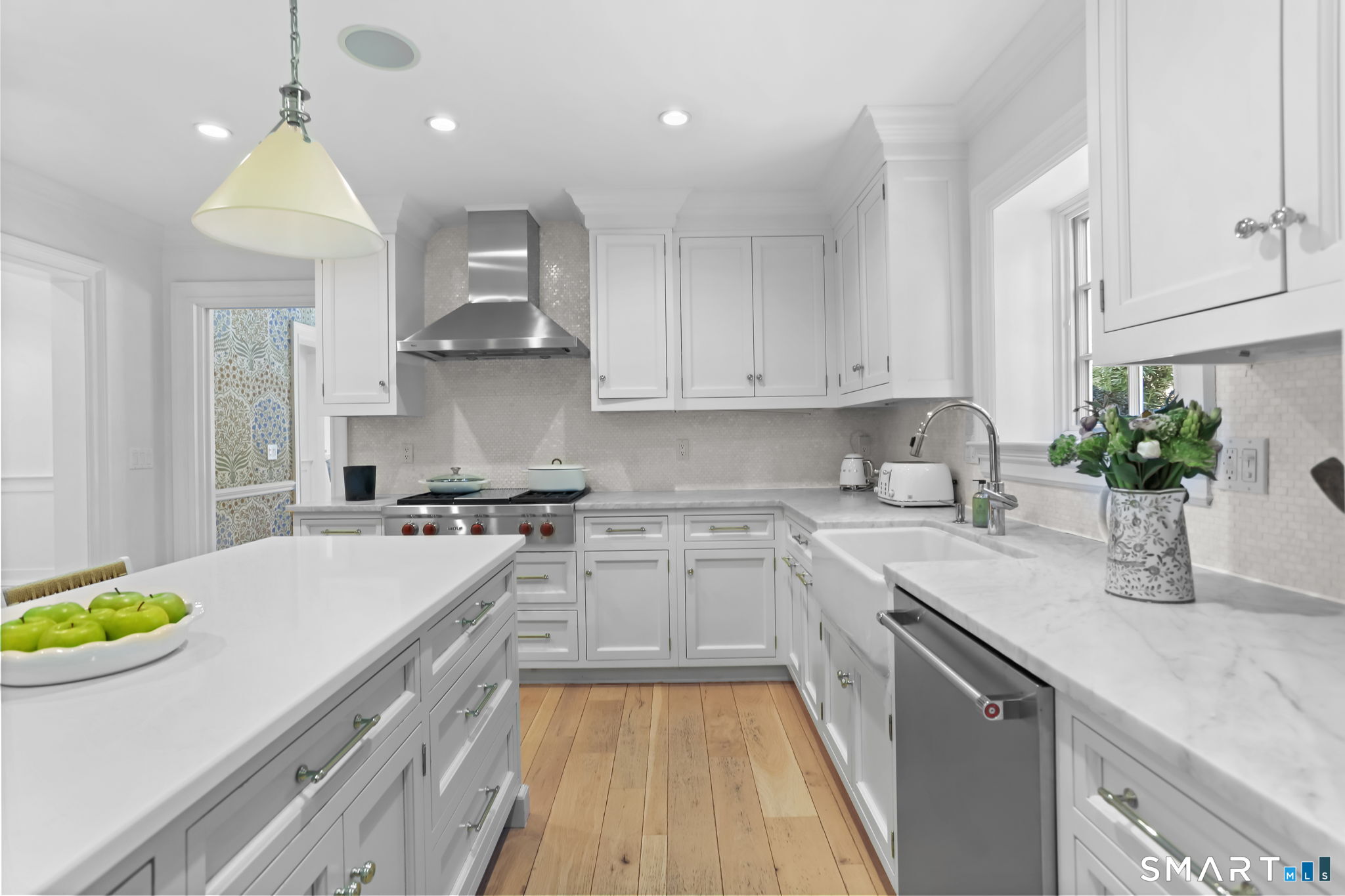 90 5 Mile River Road Darien, CT 06820 - Photo 7 of 35 a kitchen with a sink stove and white cabinets with wooden floor