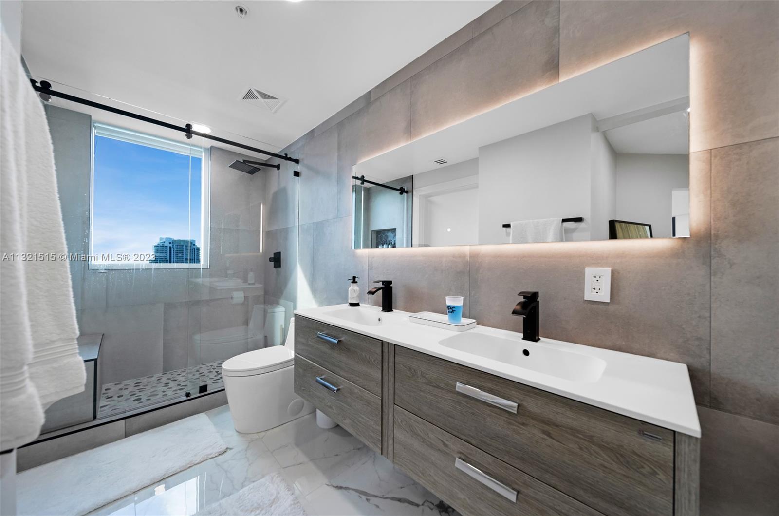 60 Southwest 13th Street, Unit 3600 Miami, FL 33130 - Photo 20 of 43 a bathroom with a double vanity sink toilet mirror and shower