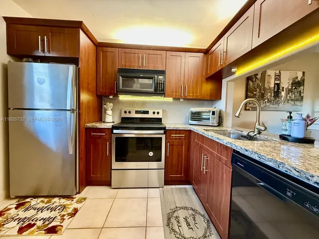 a kitchen with stainless steel appliances granite countertop a refrigerator sink and stove