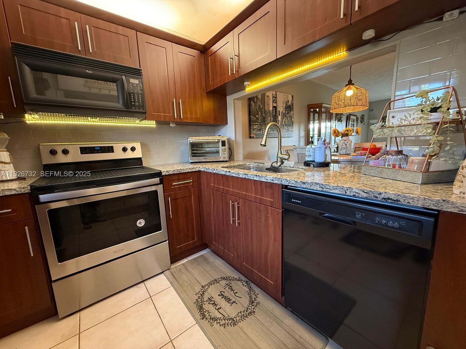 10616 Northwest 10th Street, Unit 104 Pembroke Pines, FL 33026 - Photo 13 of 47 a kitchen with stainless steel appliances granite countertop a stove a sink and a microwave