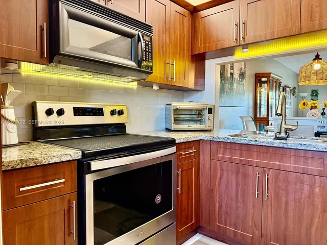 a kitchen with stainless steel appliances granite countertop a stove microwave and cabinets