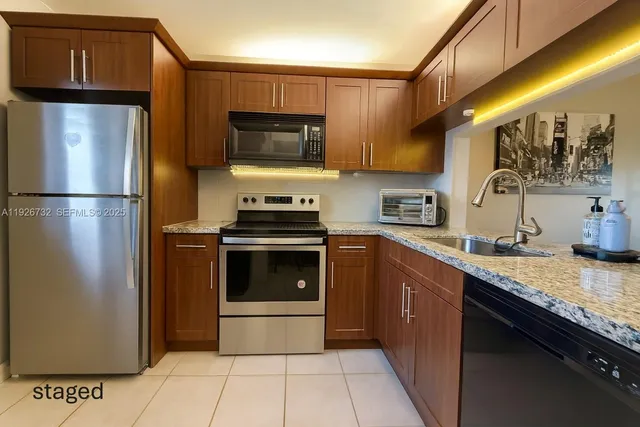 a kitchen with stainless steel appliances granite countertop a refrigerator a stove a sink and a microwave