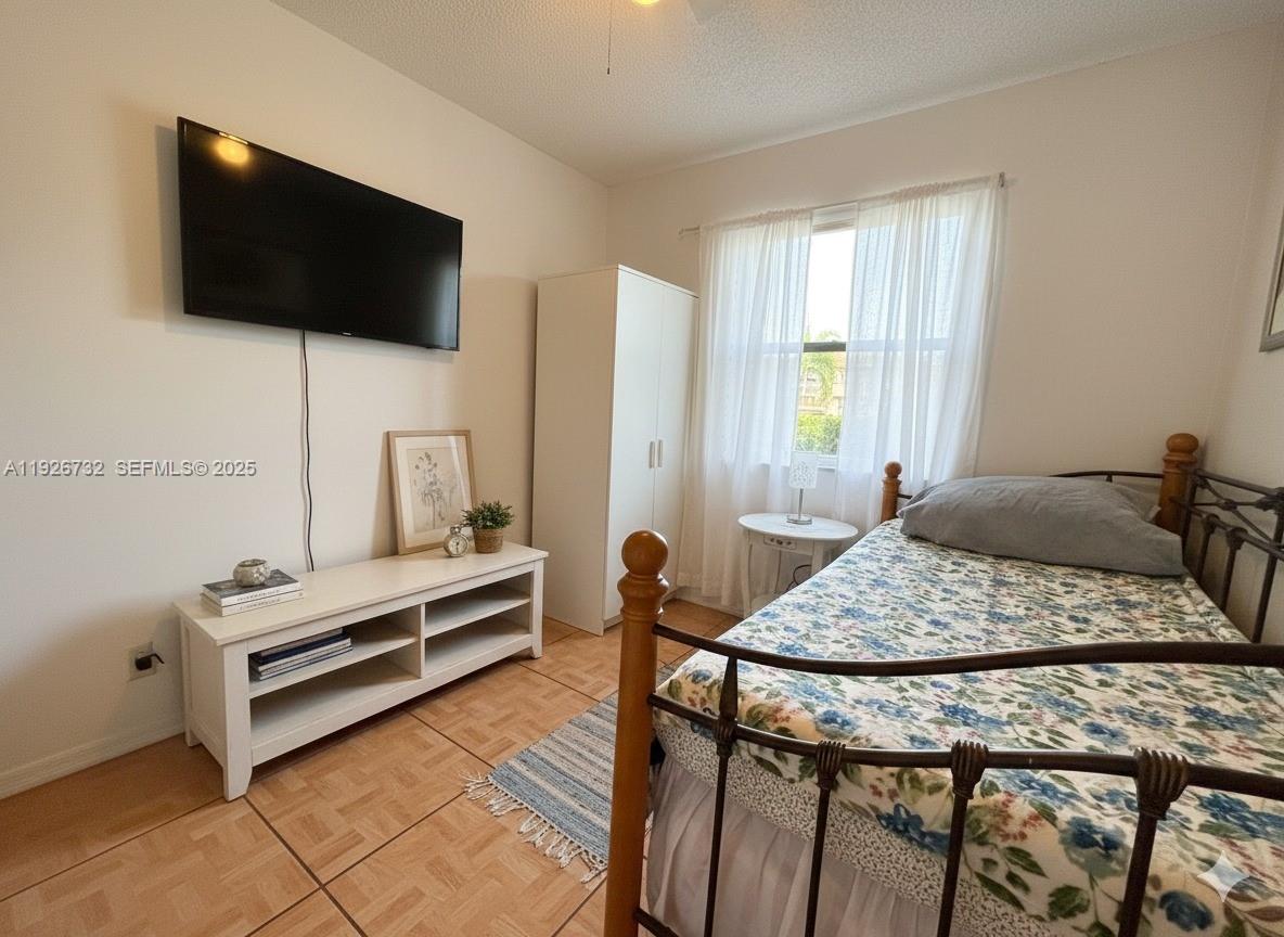 10616 Northwest 10th Street, Unit 104 Pembroke Pines, FL 33026 - Photo 28 of 47 a bedroom with a bed and a flat screen tv