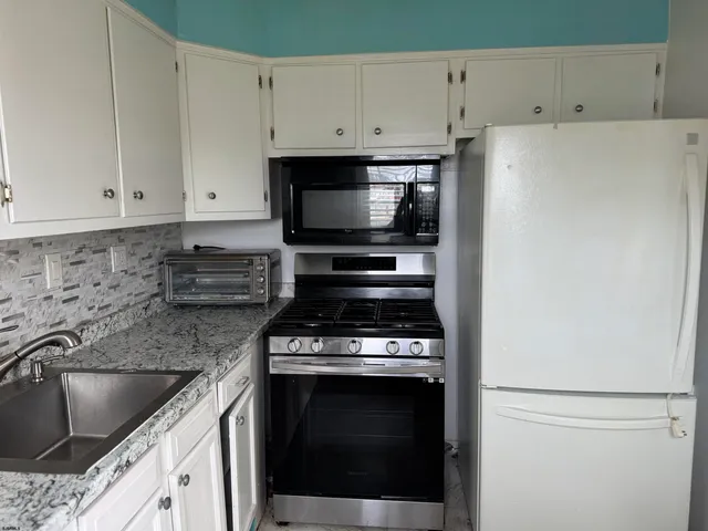 a kitchen with granite countertop a sink stove and white cabinets