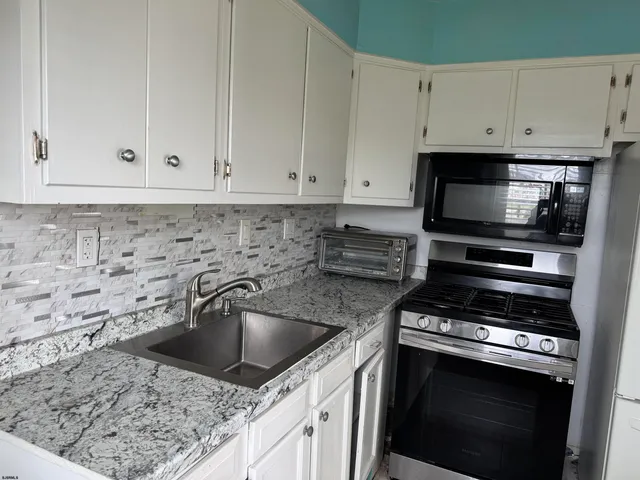 a kitchen with granite countertop a sink stove and cabinets