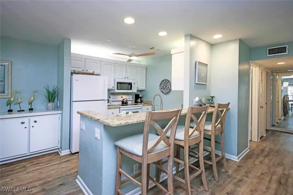 a kitchen with stainless steel appliances kitchen island granite countertop a table chairs sink and cabinets