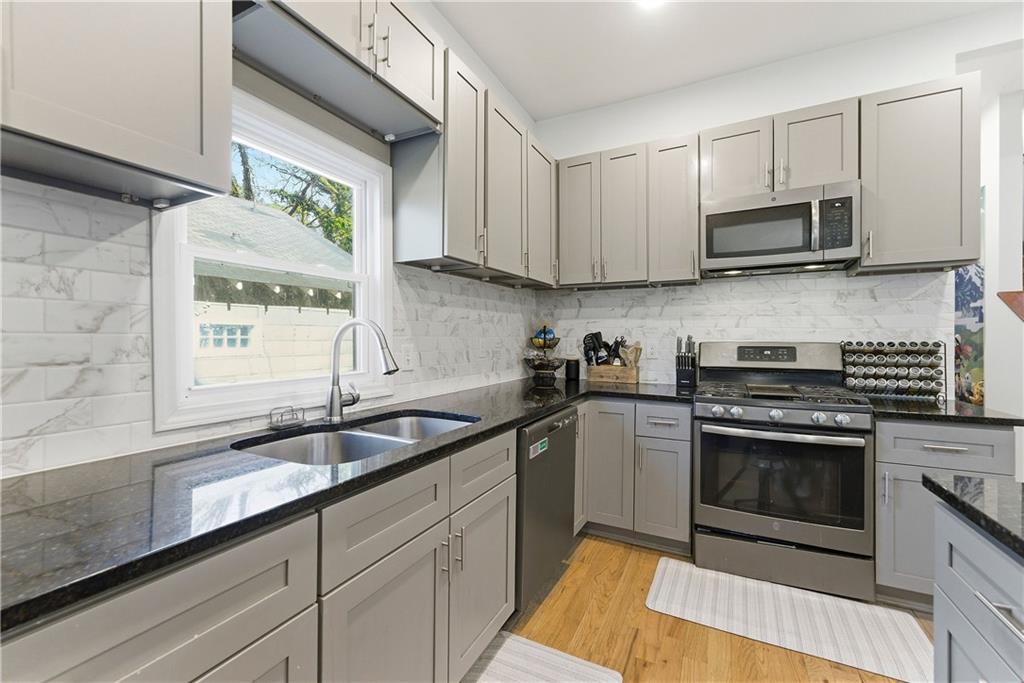 902 Gaston Street Southwest Atlanta, GA 30310 - Photo 10 of 36 a kitchen with stainless steel appliances granite countertop a sink a stove a microwave and wooden cabinets