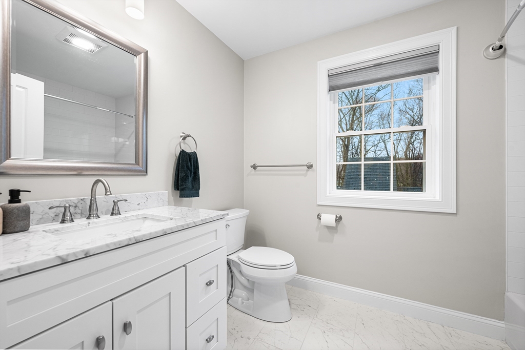 32 Fraser Road Framingham, MA 01702 - Photo 25 of 37 a bathroom with a granite countertop toilet a sink a mirror and a window