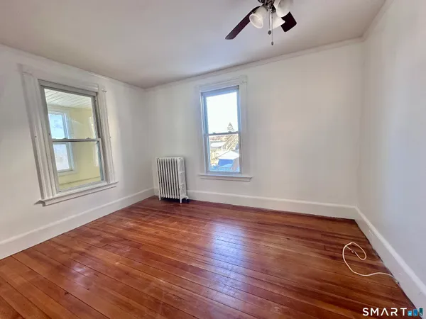 an empty room with wooden floor cabinet and windows