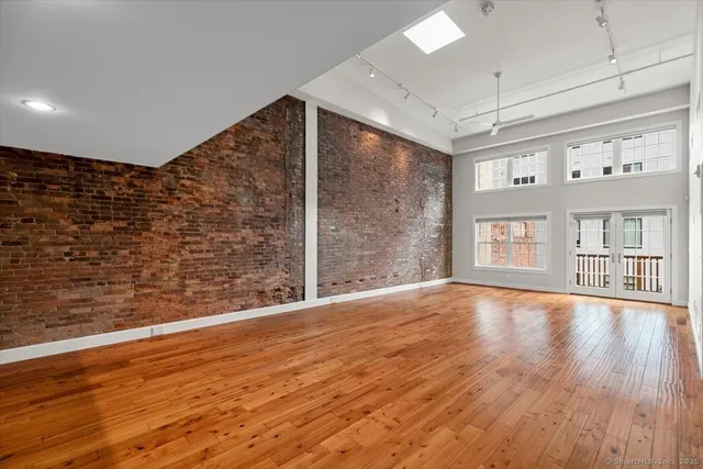 a view of an empty room with window and wooden floor