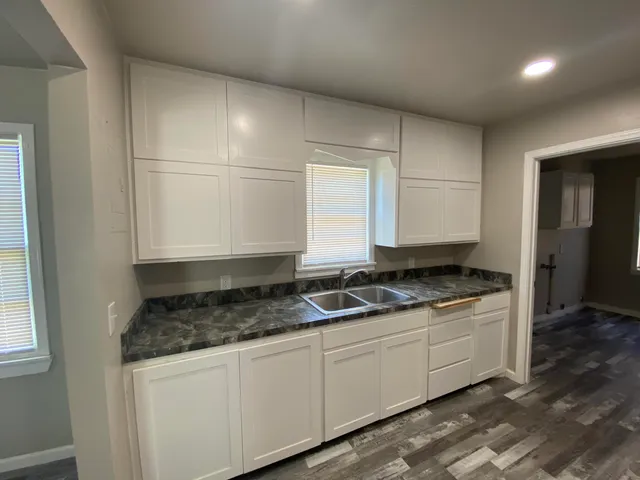 a kitchen with granite countertop a sink stove and cabinets