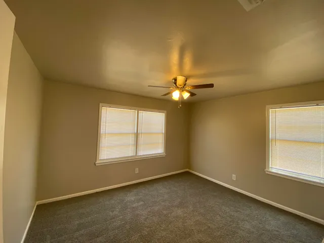 an empty room with windows and fan