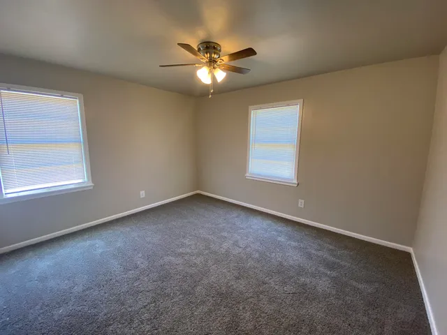 an empty room with windows and fan