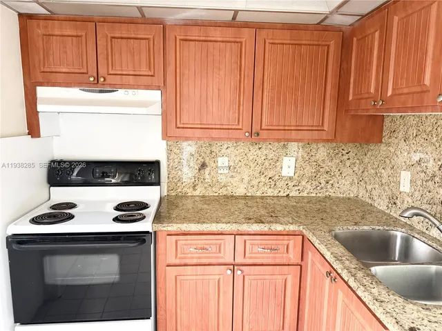 a kitchen with granite countertop a sink stove and cabinets