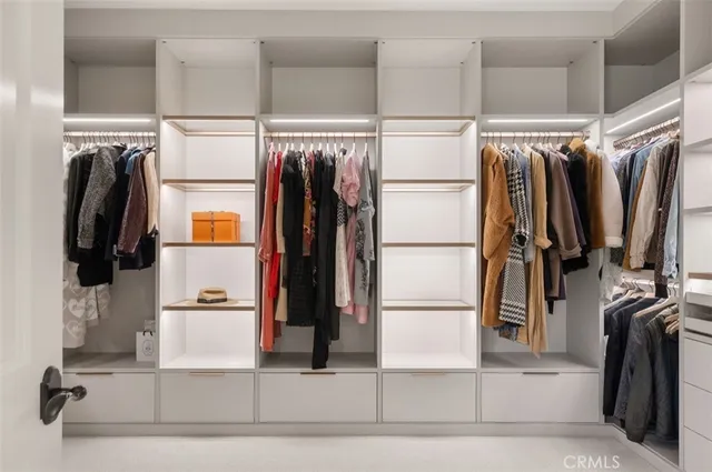 a view of walk in closet with clothes and shoes
