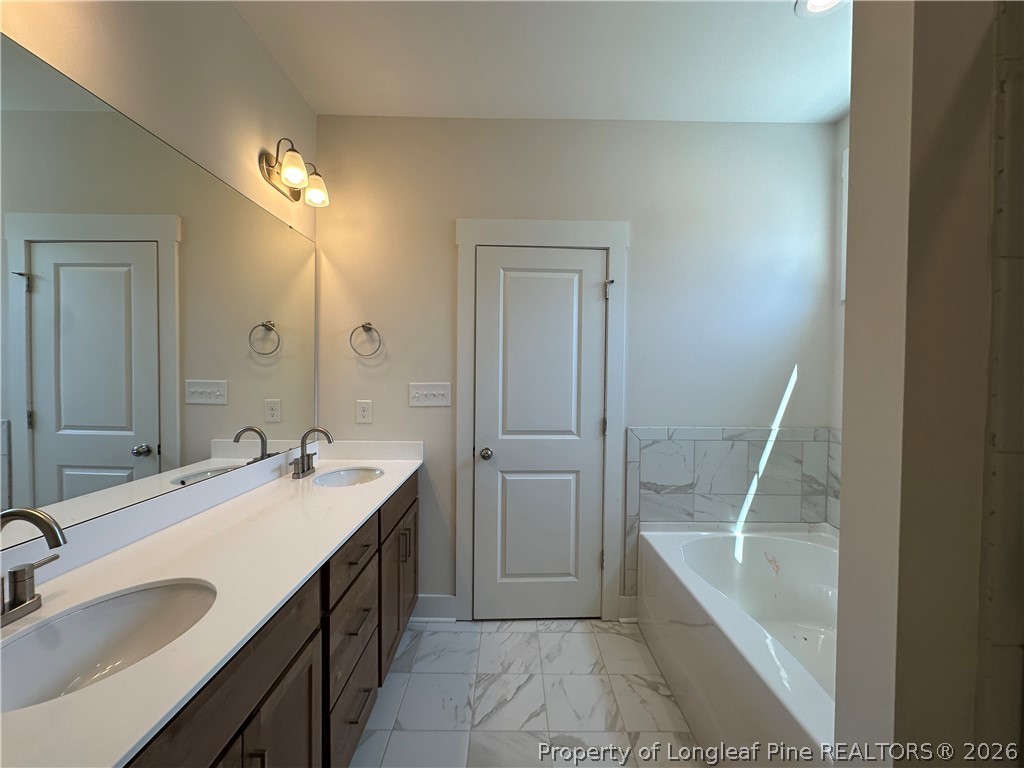 2908 Calloway Road Raeford, NC 28376 - Photo 15 of 25 a bathroom with a double vanity sink a mirror and a bathtub