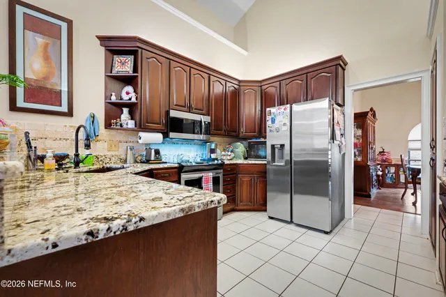 a kitchen with stainless steel appliances granite countertop a refrigerator a stove and a sink with wooden cabinets