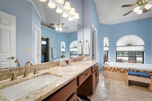 a large bathroom with a granite countertop double vanity sink a mirror and a bathtub