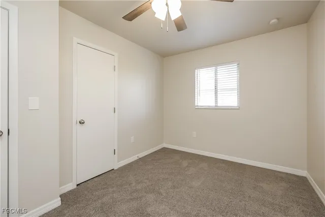 an empty room with a chandelier fan and windows