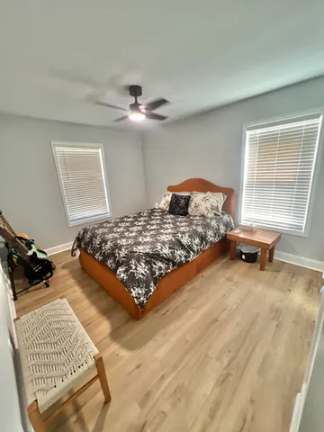 a bedroom with a bed and dresser with wooden floor