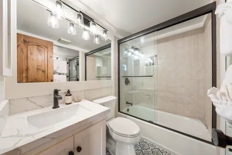 a bathroom with a sink a toilet and shower