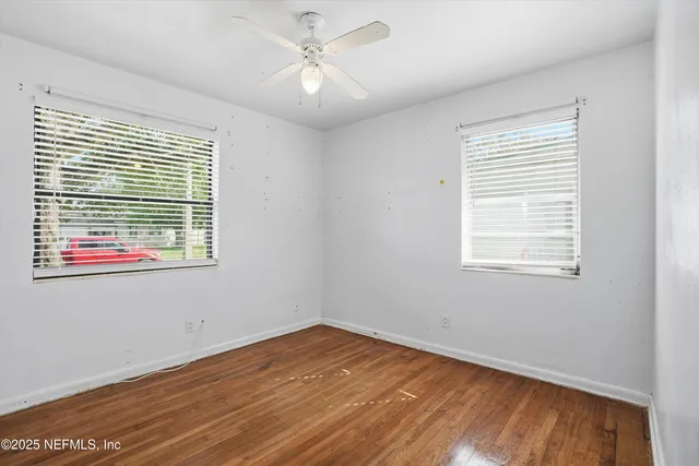 a view of empty room with wooden floor and fan