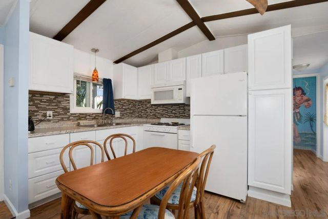 a kitchen with stainless steel appliances granite countertop a table chairs and a refrigerator