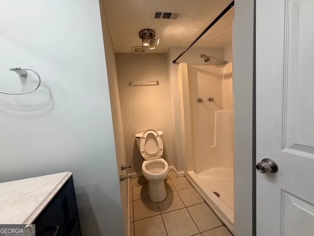 a bathroom with a granite countertop toilet and a shower