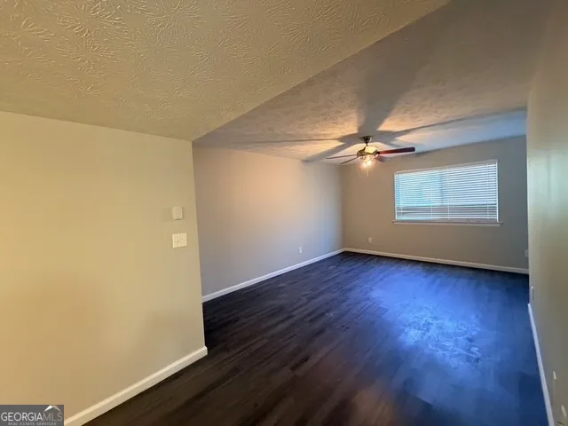 an empty room with wooden floor fan and windows