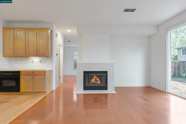 a living room with stainless steel appliances granite countertop a fireplace a stove top oven a chimney and a window