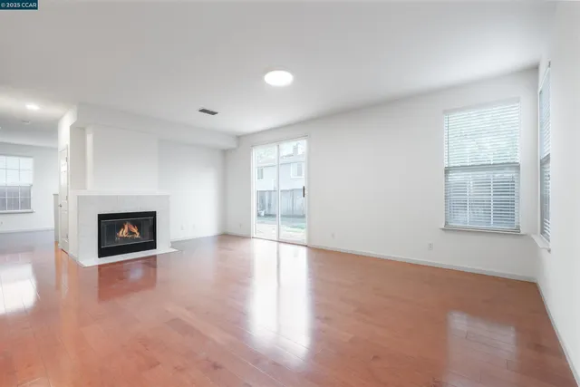 an empty room with windows and fireplace