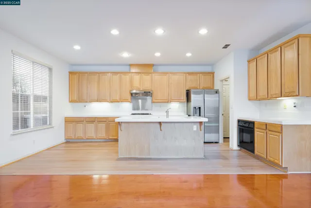a large white kitchen with kitchen island a sink a stove and a refrigerator