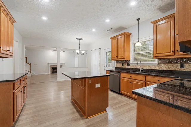 a kitchen with stainless steel appliances granite countertop wooden cabinets a sink dishwasher a stove and a refrigerator