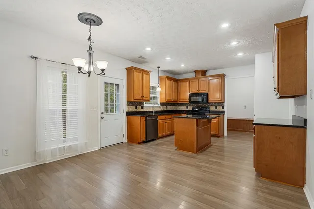 a kitchen with stainless steel appliances kitchen island granite countertop wooden floors and granite counter tops