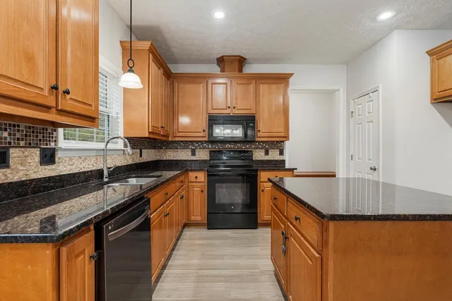 a kitchen with stainless steel appliances granite countertop a sink a stove and a microwave