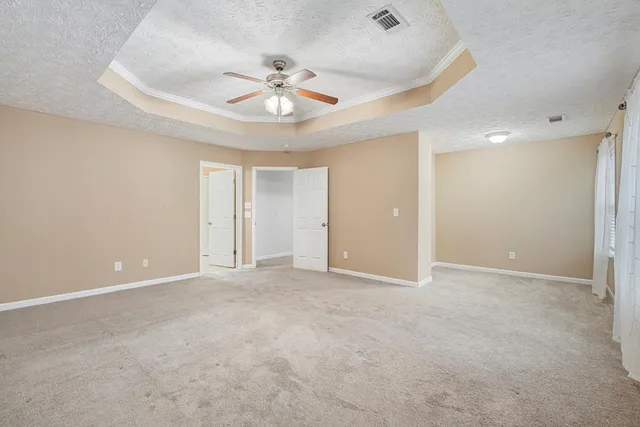 an empty room with chandelier fan and windows