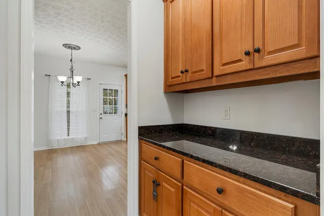 a view of a kitchen with granite countertop white cabinets and a wooden floor