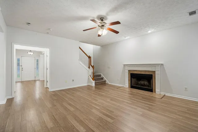 a view of an empty room with wooden floor fireplace and a window