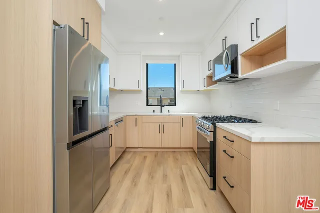 a kitchen with a sink a counter top space stainless steel appliances and cabinets