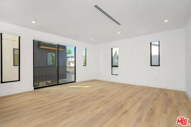 a view of an empty room with wooden floor and windows